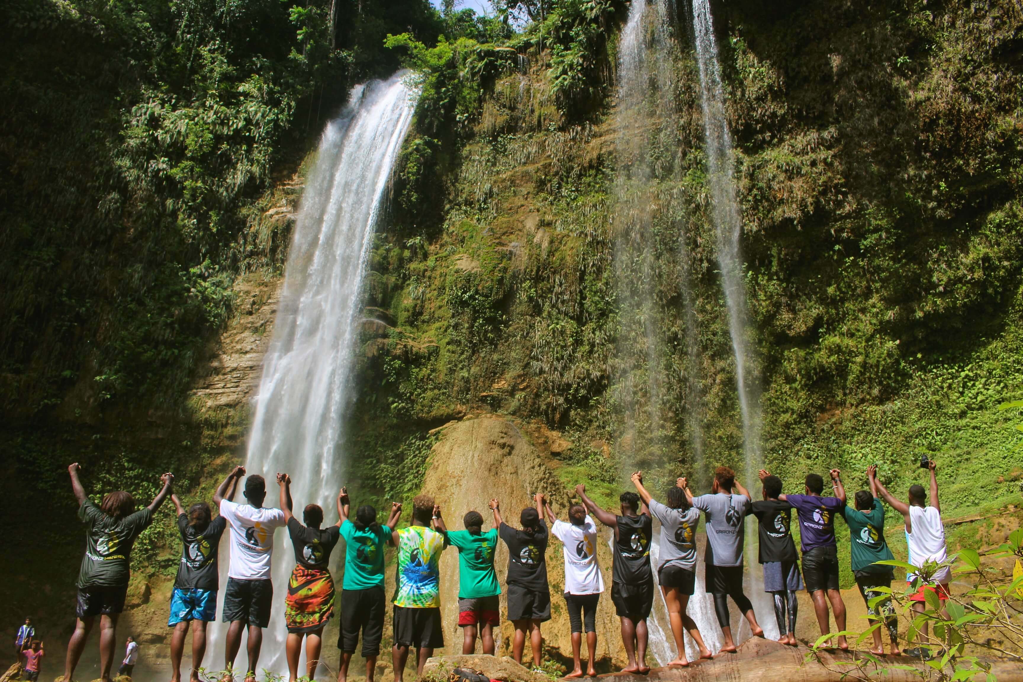 Solomon Islands with a group of people standing in front of a waterfall
