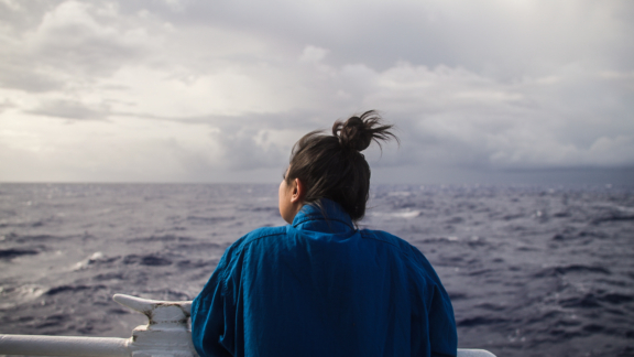 A woman looking at the ocean.
