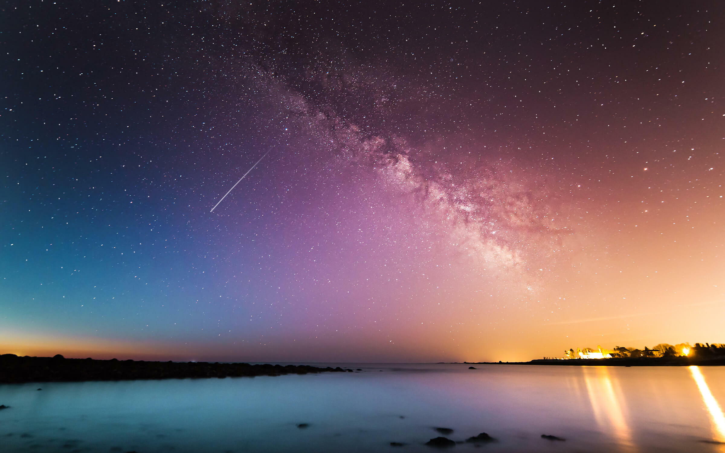 Colorful starry sky over water and land