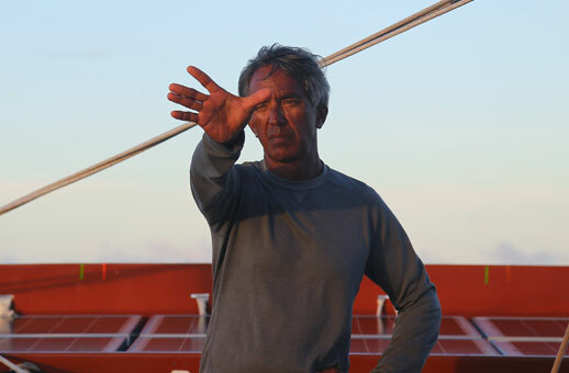 A man reaches outward while on a boat